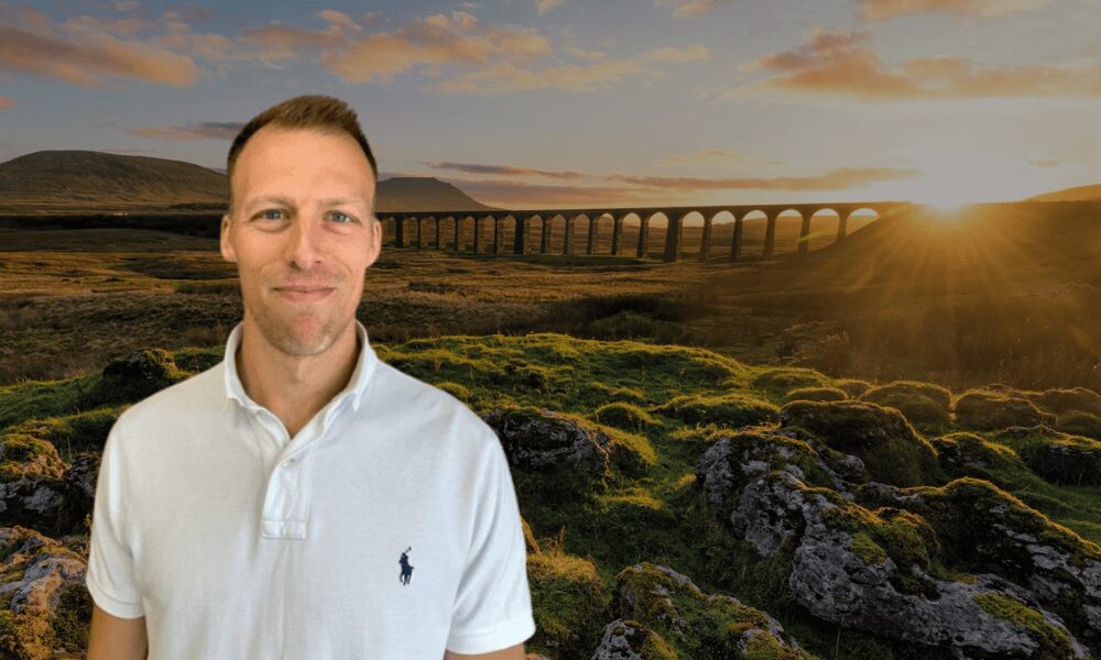 A photo of our consultant Ed smiling, super imposed onto a photo of viaducts over the yorkshire countryside at sunset