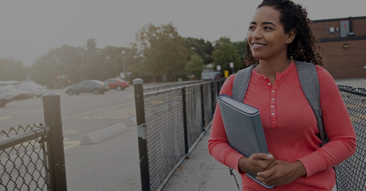 Photo of a female teaching walking away from school, books in hand with text that says 'what to consider when resigning from teaching jobs'